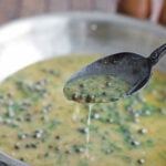 Lemon caper butter sauce dripping off of a tilted spoon
