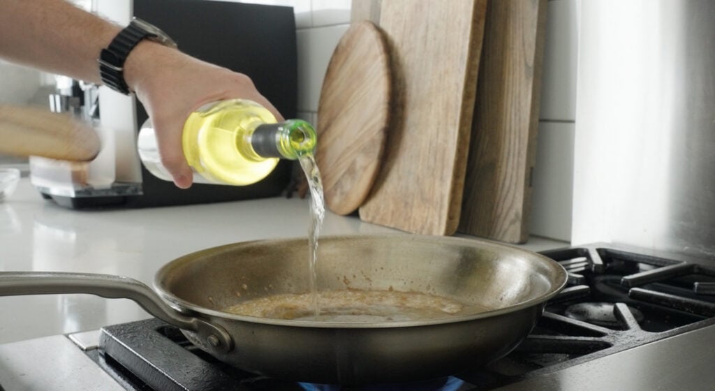 Pouring white wine in the pan