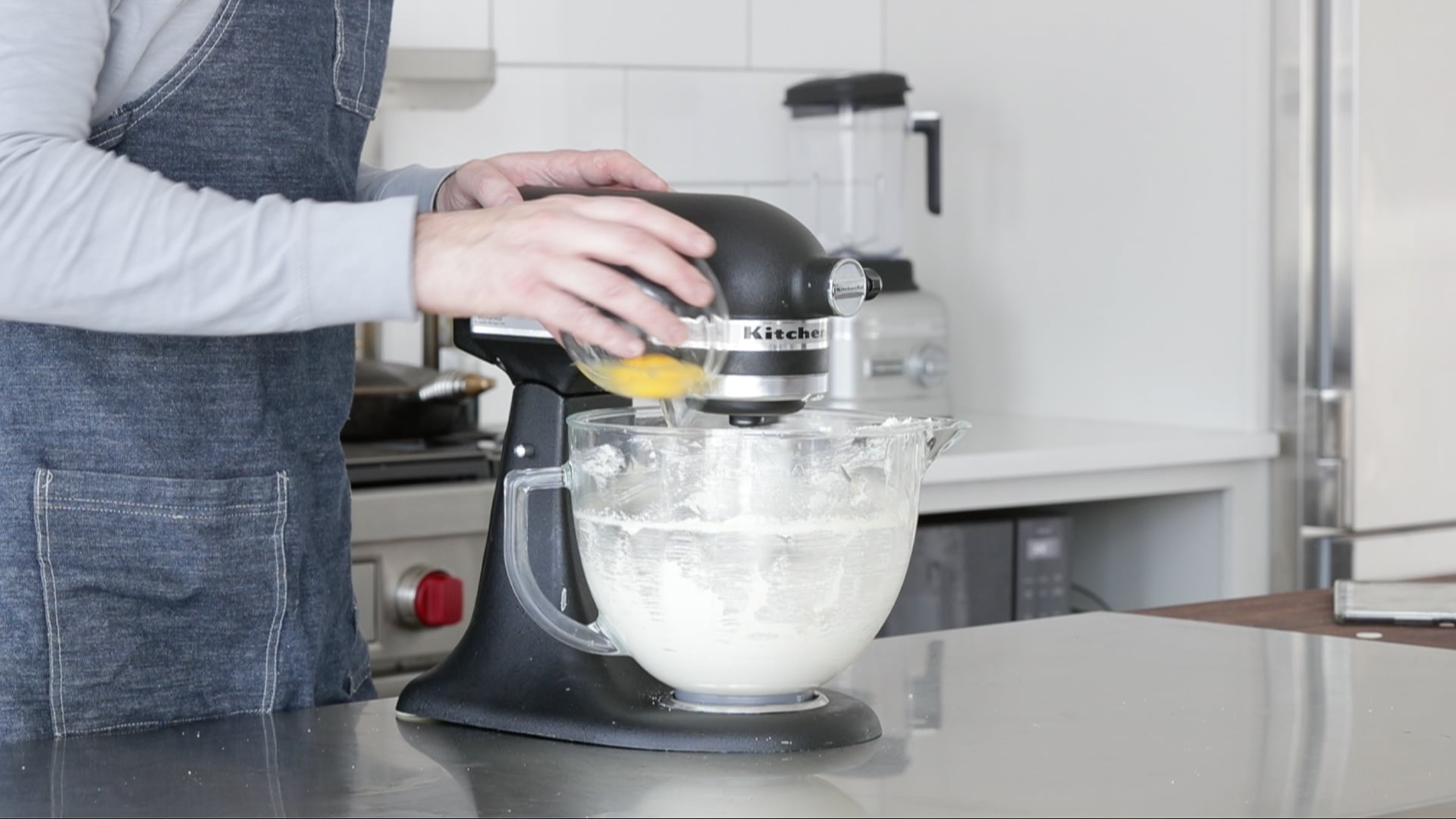 adding eggs to a mixer