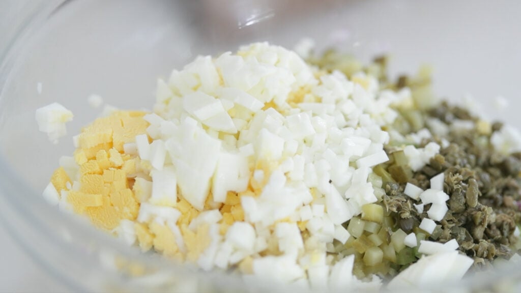 adding hard boiled eggs to a bowl with vegetables