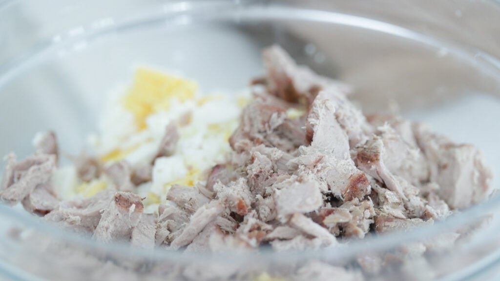 adding fresh cooked tuna to a bowl