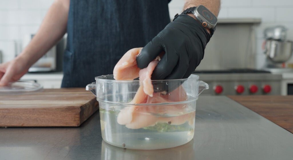 Large bowl containing the wet ingredients with the chicken breasts being added in