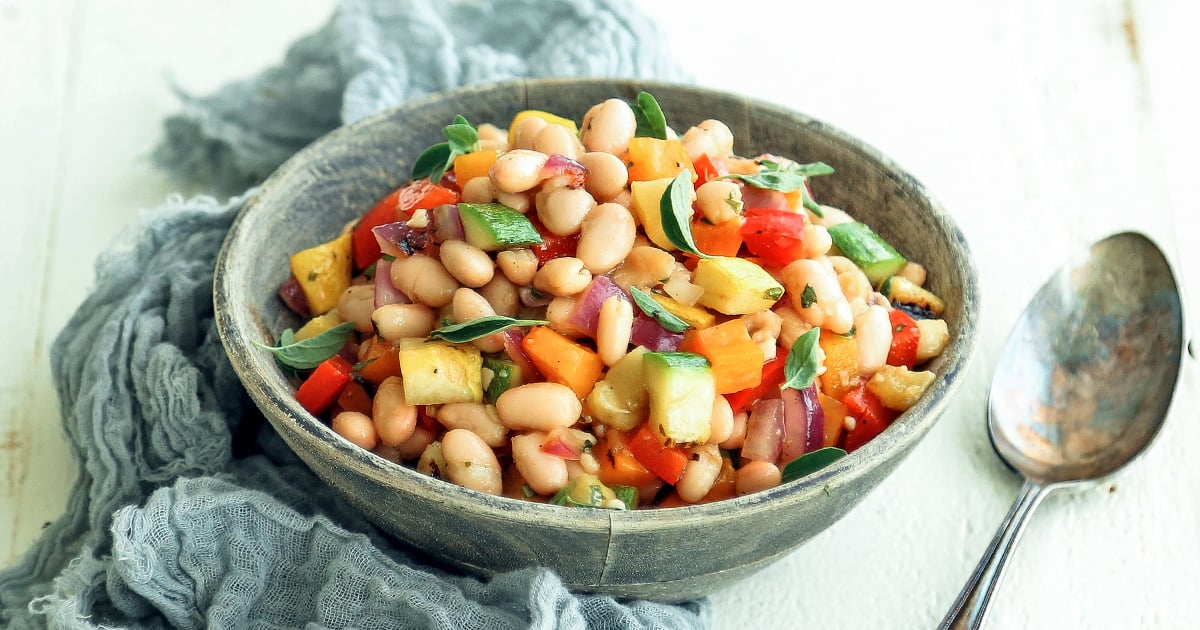 adding herbs to a mediterranean bean salad