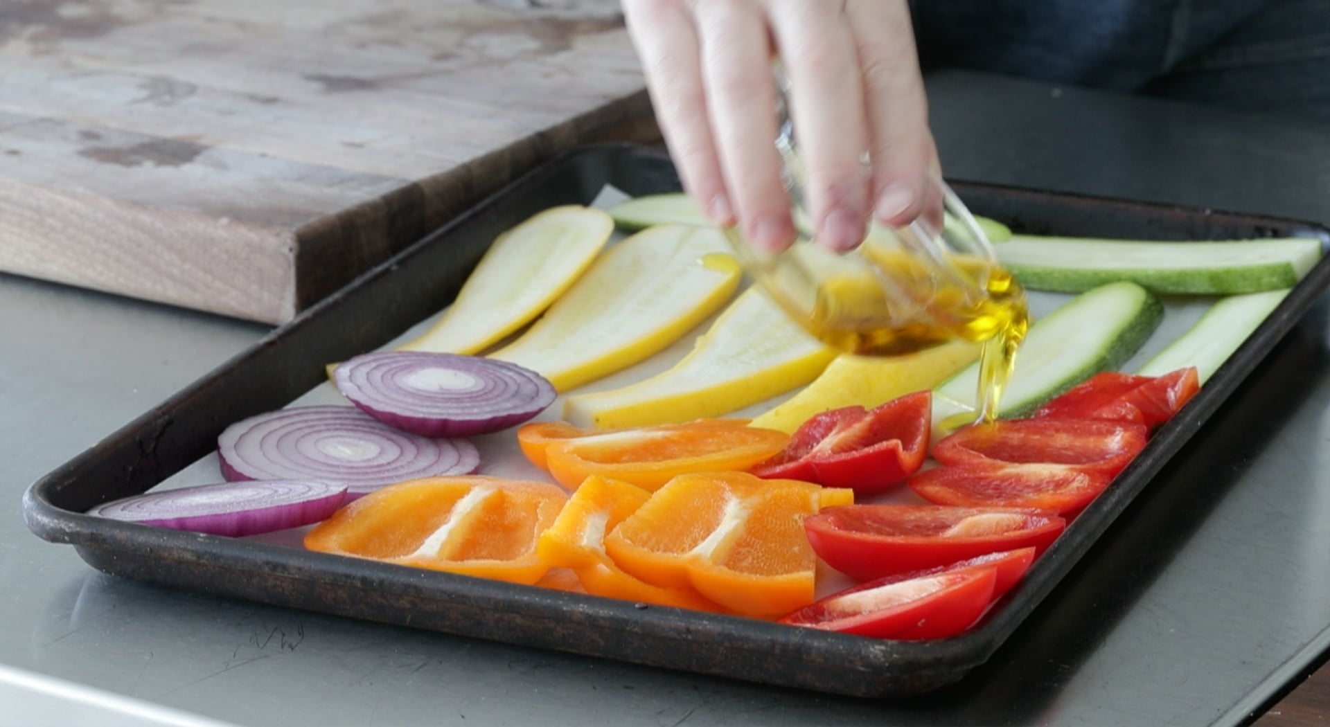 adding olive oil to a sliced vegetables