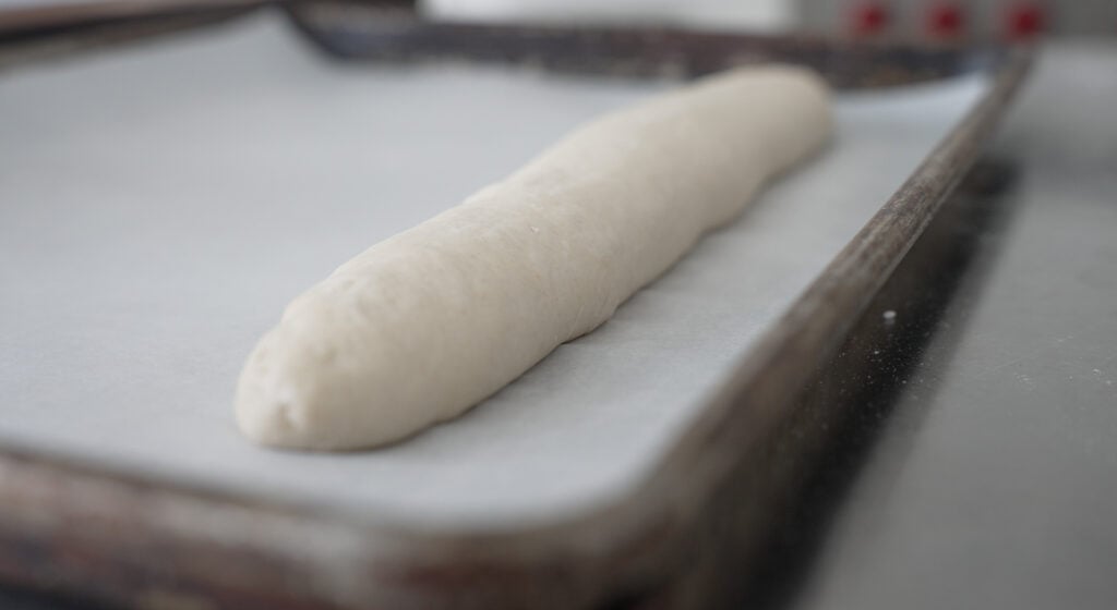 A baguette on a sheet tray lined with parchment paper