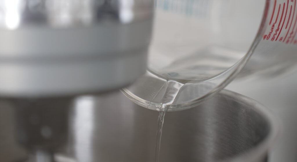pouring water into a bowl of a mixer