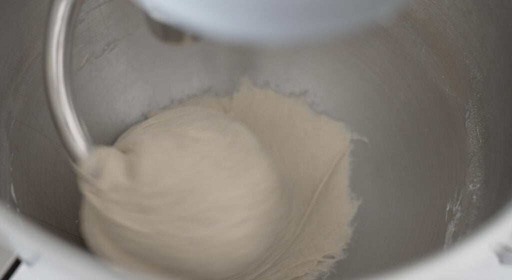 a ball of dough forming in the bowl of a stand mixer