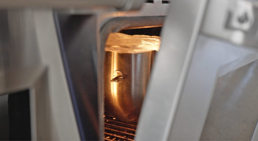 a mixing bowl in an oven with the light on and door slightly open