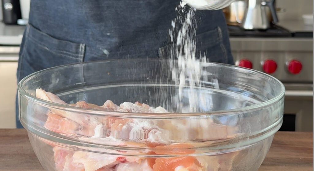 Adding baking powder to bowl with wings