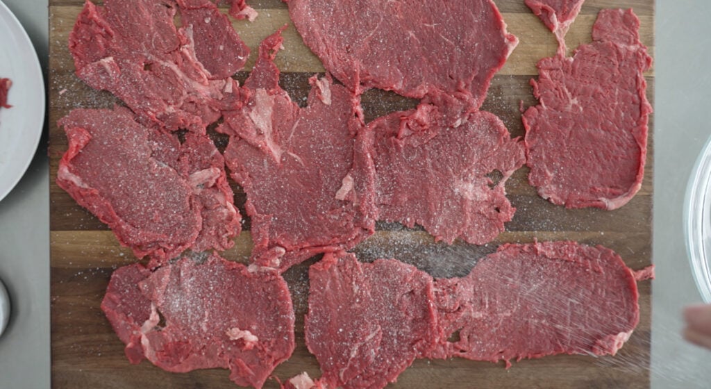 9 thin slices of meat layed out and seasoned