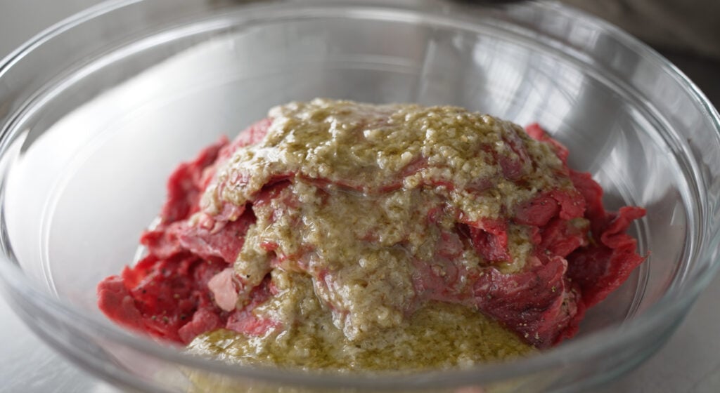 Beef slices in a bowl with marinade poured over top