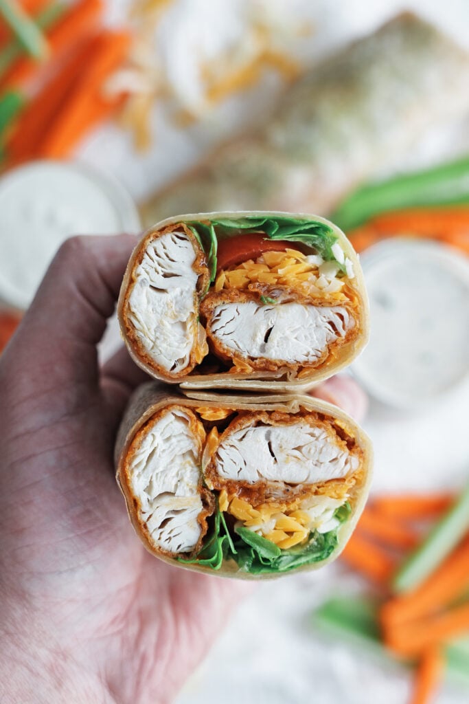 a side view of a buffalo chicken wrap cut in half and stacked one on top of the other