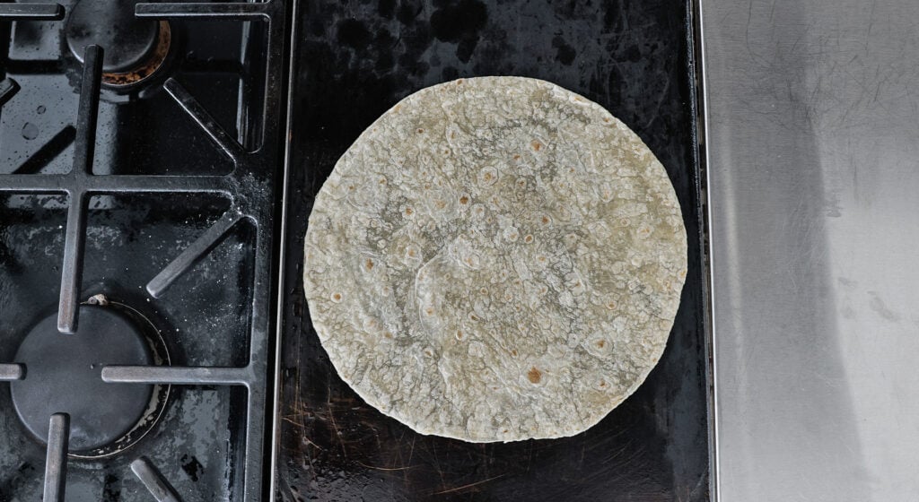 a flour tortilla on a griddle on the stove