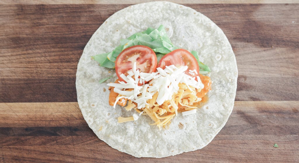Buffalo chicken tenders, lettuce, tomato and cheese on a flour tortilla