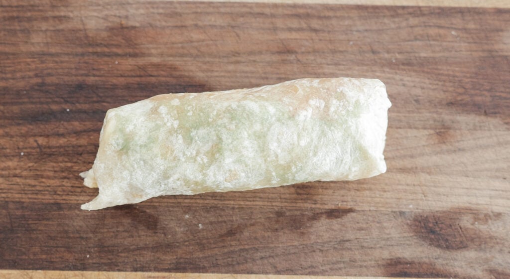 A tightly rolled wrap on a cutting board