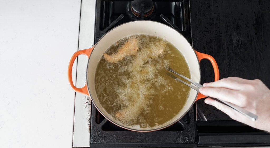Pieces of chicken frying in hot oil