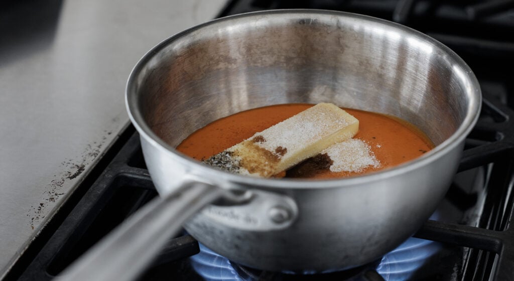 A pot on a stove with the flame under it and the butter melting into the other ingredients