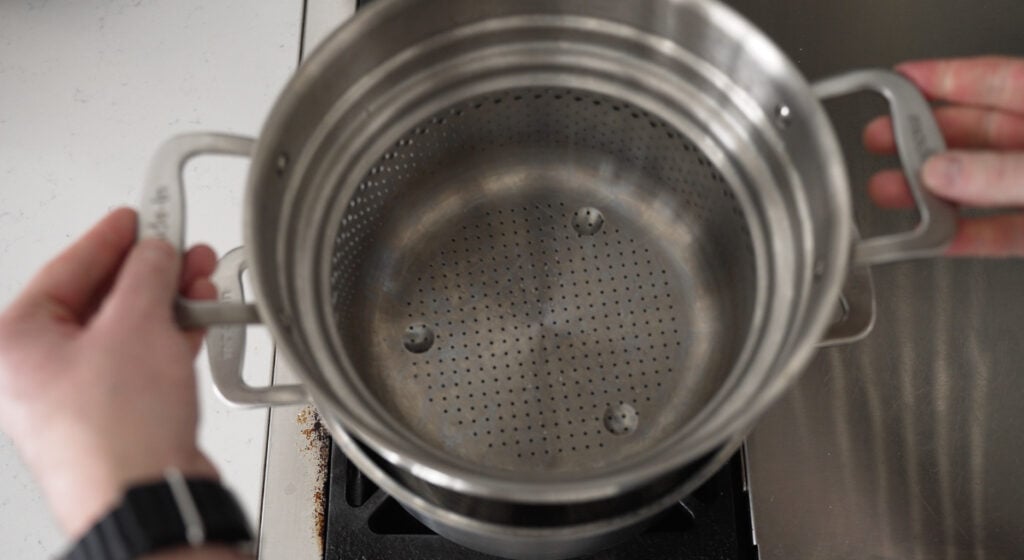 a steamer insert being placed in a large pot of water