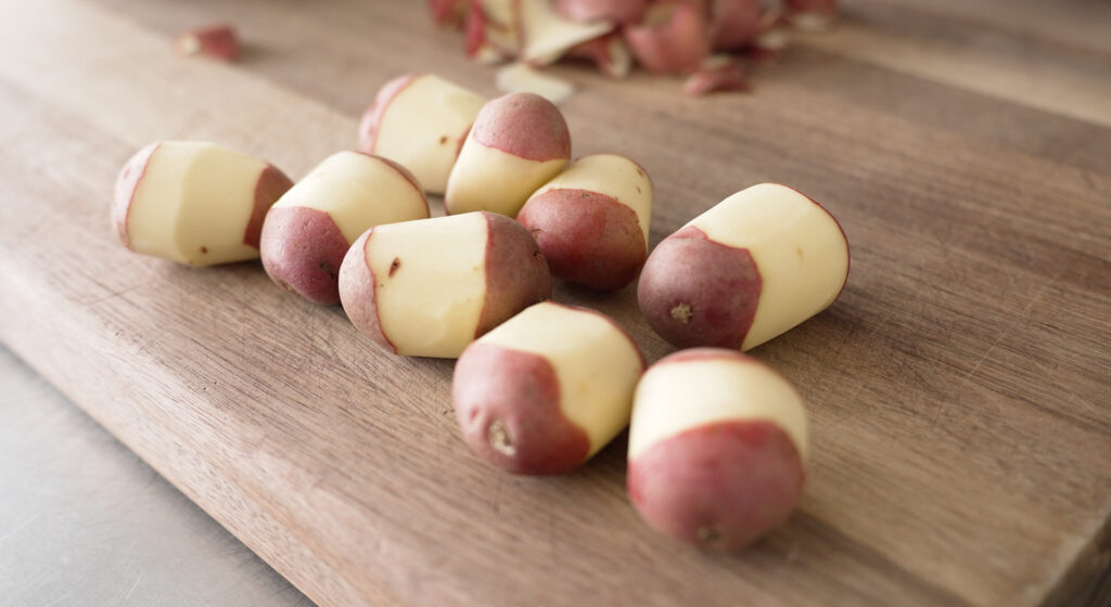 Red Potatoes laying on a cutting board with only the centers peeled 