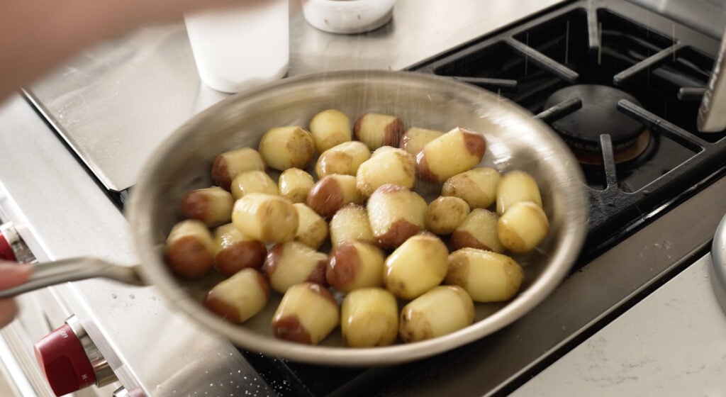 Potatoes added to the butter in the pan being sprinkled with salt