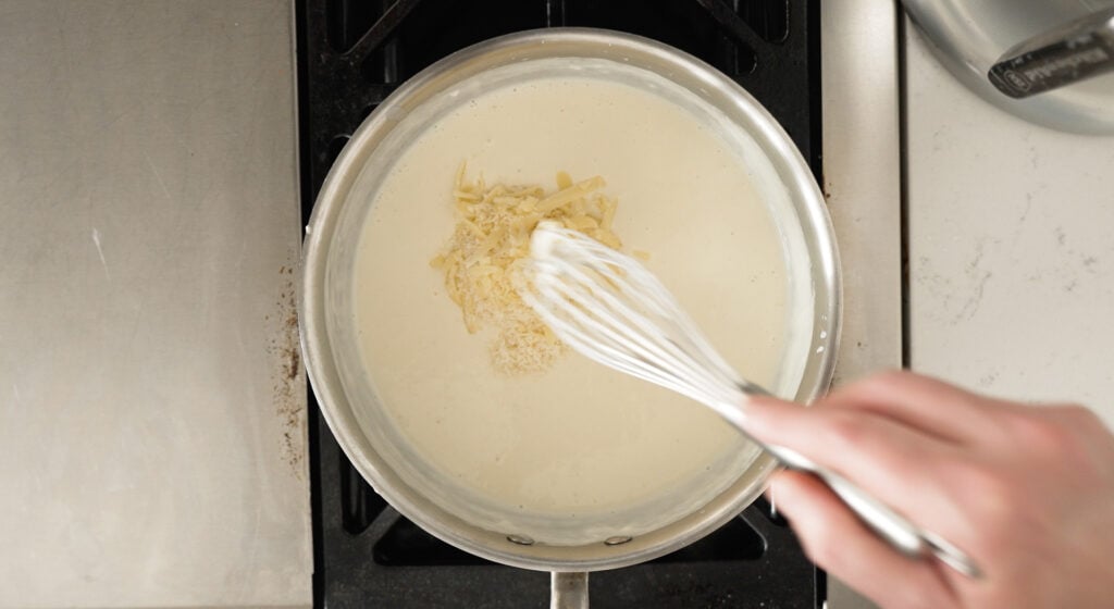 whisking cheese into the white b&eacute;chamel sauce
