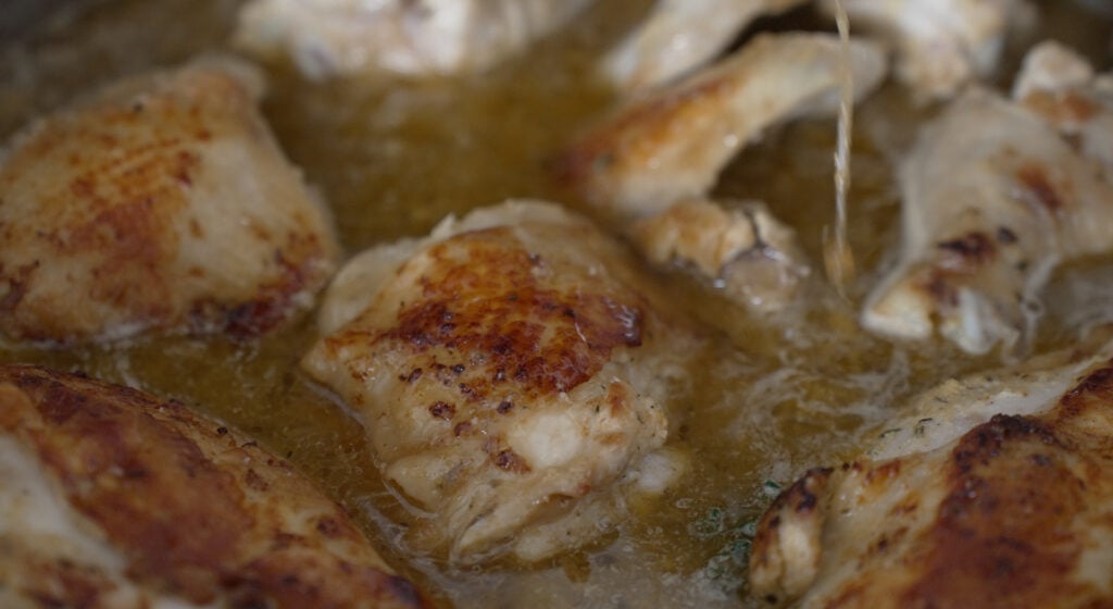 close up of browned chicken pieces in chicken broth