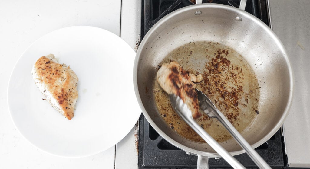 Removing the browned, cooked chicken breasts from the pan