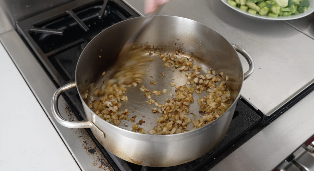 large pot on the stove with chopped browned onions and leeks inside
