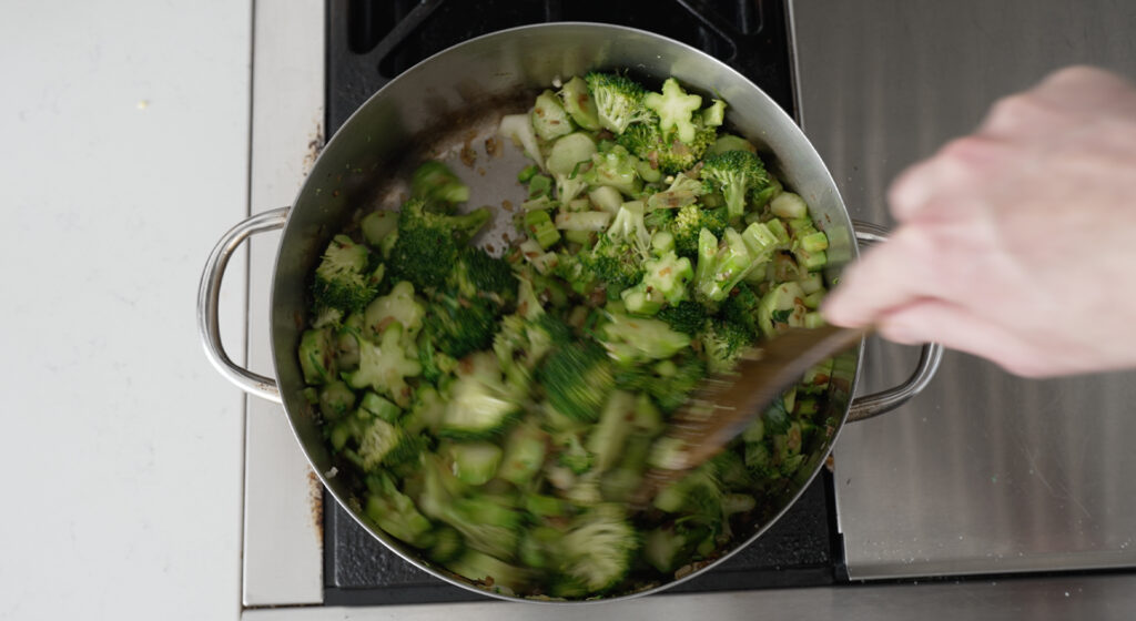 stiring the broccoli in the pot with a wooden spoon