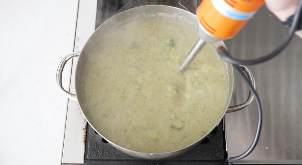 An immersion blender in the pot of soup