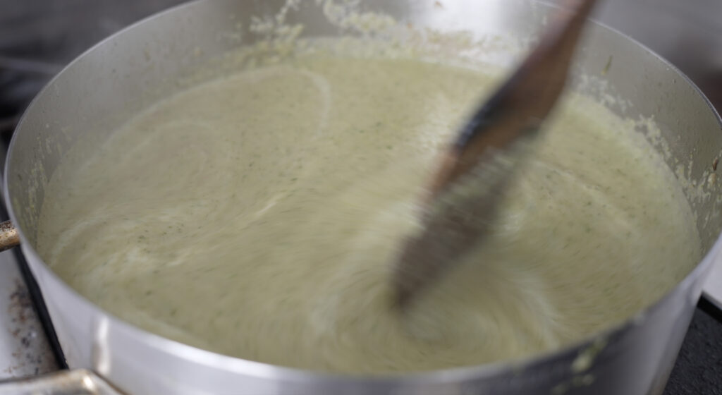 close up of the blended soup being stirred with a wooden spoon