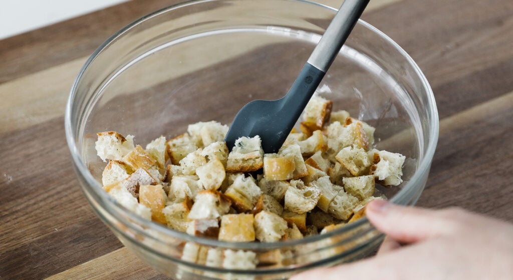 mixing cubed bread in a bowl
