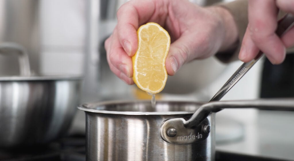 squeezing a lemon half into the pot