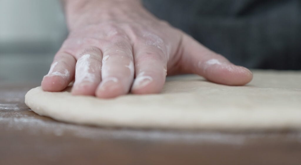 pressing down on dough on flat surface