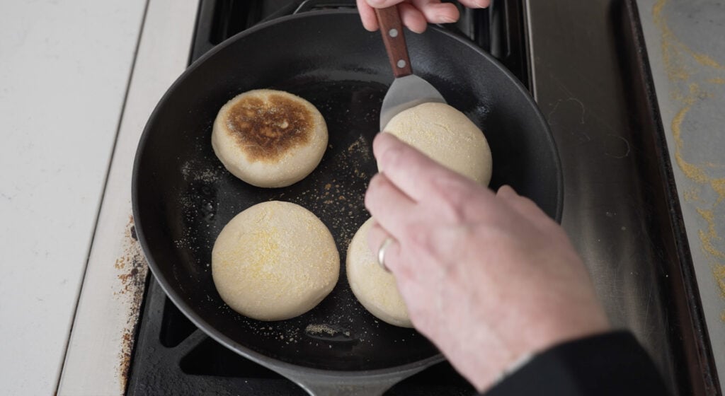 using a turner to turn a cooked english muffin