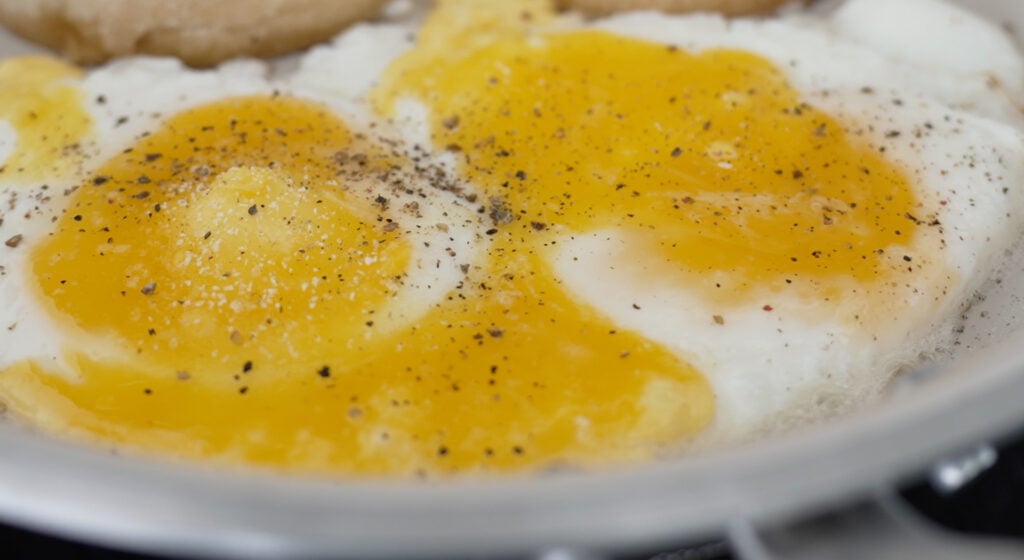 Close up of fried egg seasoned with salt and pepper