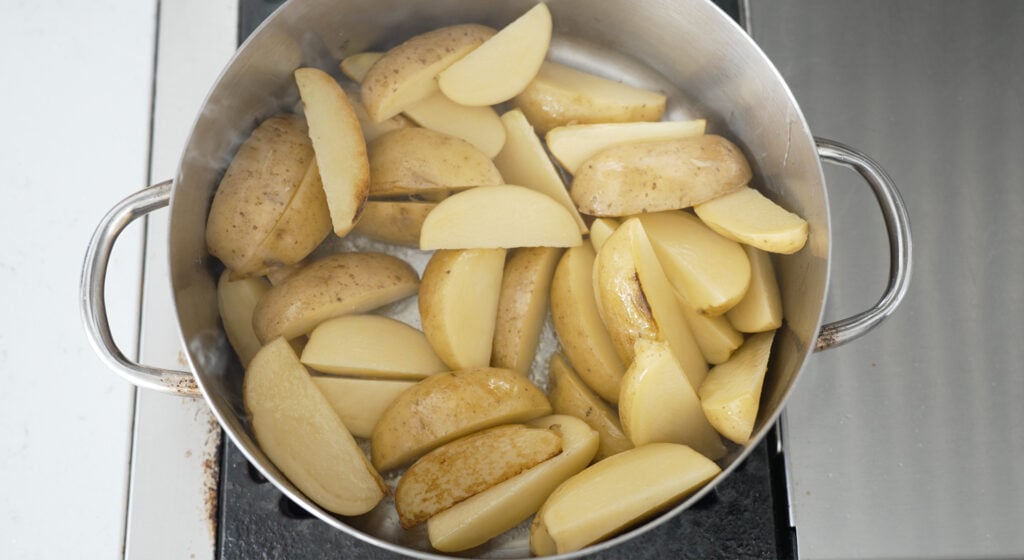 uncooked, quartered potatoes in a large rondeau