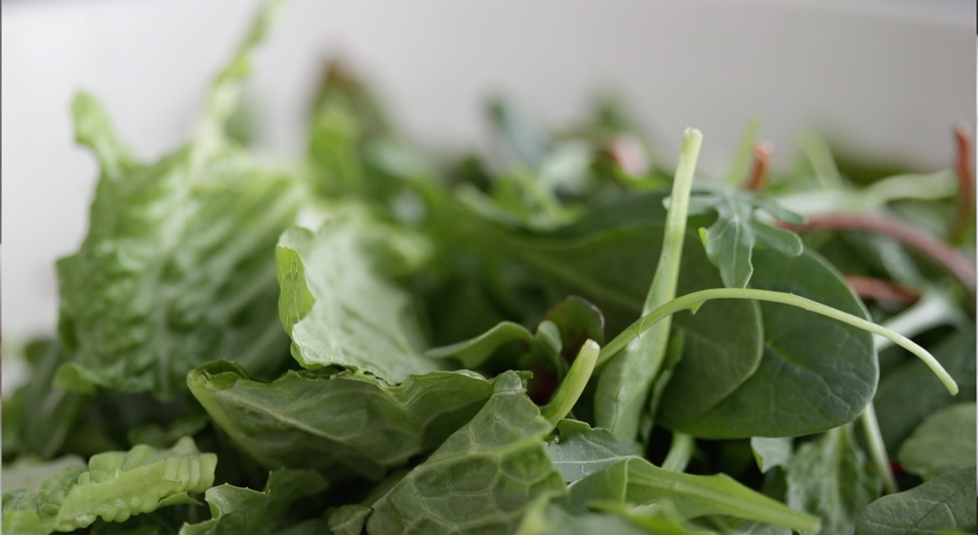 adding greens to a bowl