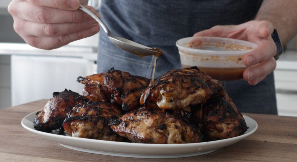 spooning extra marinade on the grilled chicken