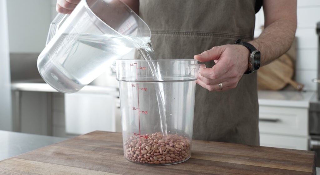 Pouring water into a large container with dried beans