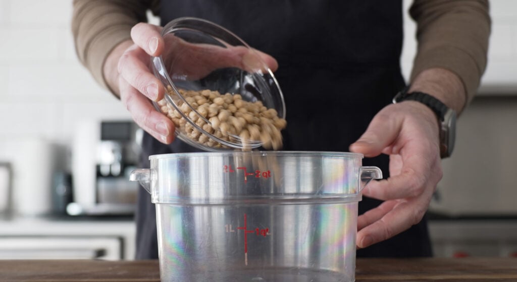 Pouring dry chickpeas into a large container