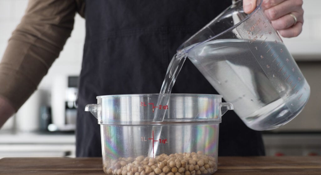 Pouring water into container with chickpeas