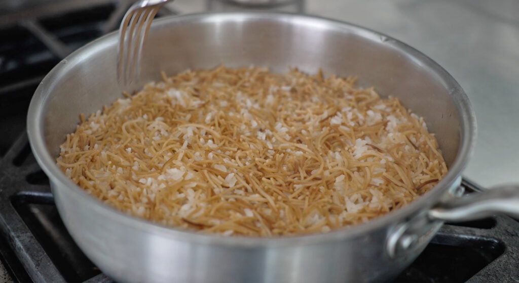 A fork on the side of a pan containing noodles and rice