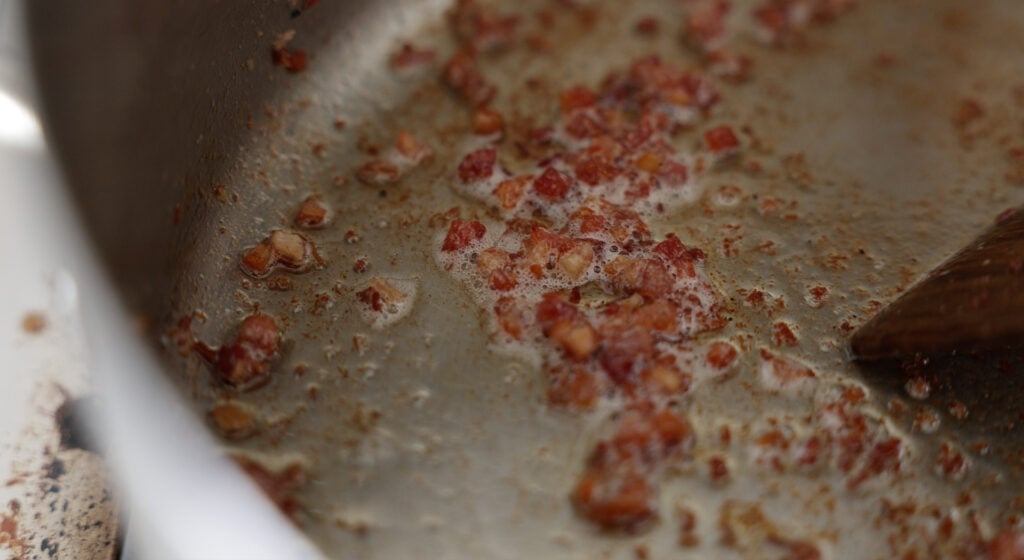 browned pieces of pancetta in a pan