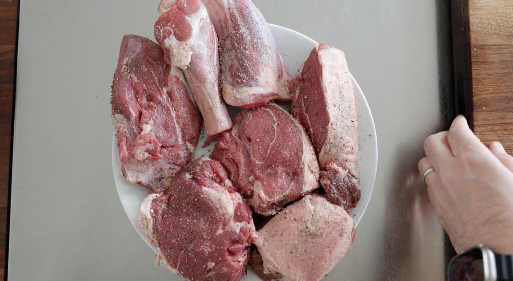 8 pieces of seasoned, uncooked lamb on a plate