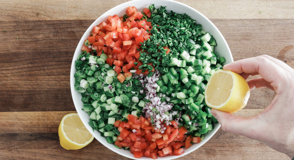 squeezing a fresh lemon half over the salad