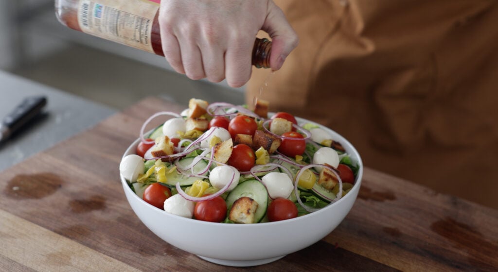 Pouring red wine vinegar over top of the salad
