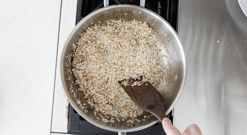 Stirring rice into the pan with onions