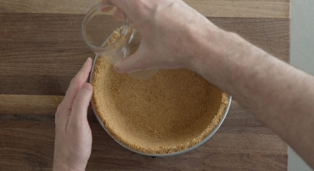 using a glass to press crust into a springform pan