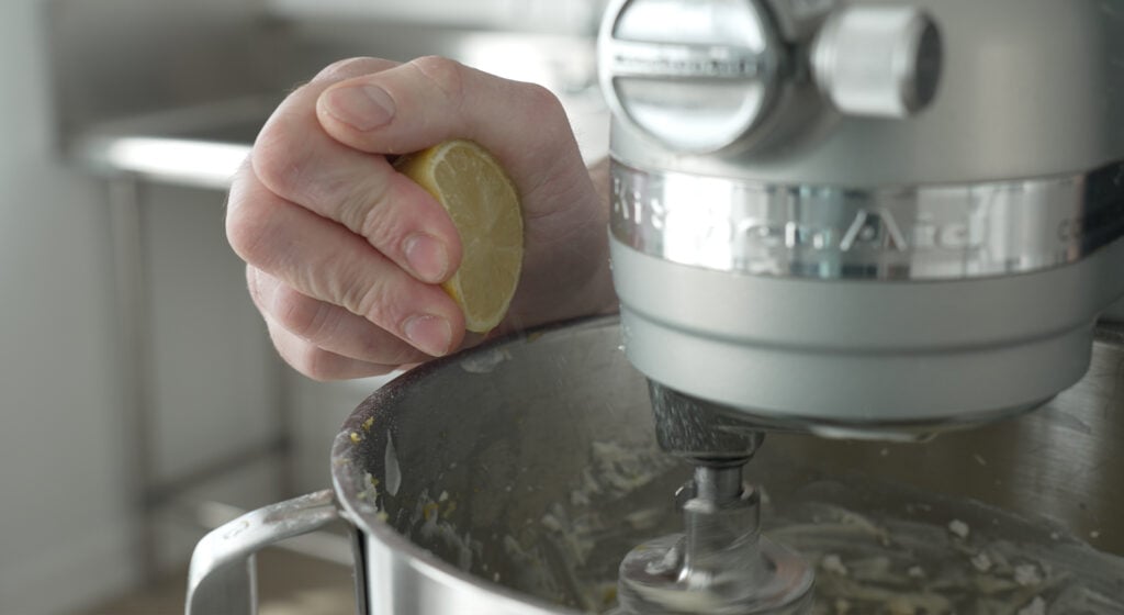 Squeezing a half lemon into the mixing bowl